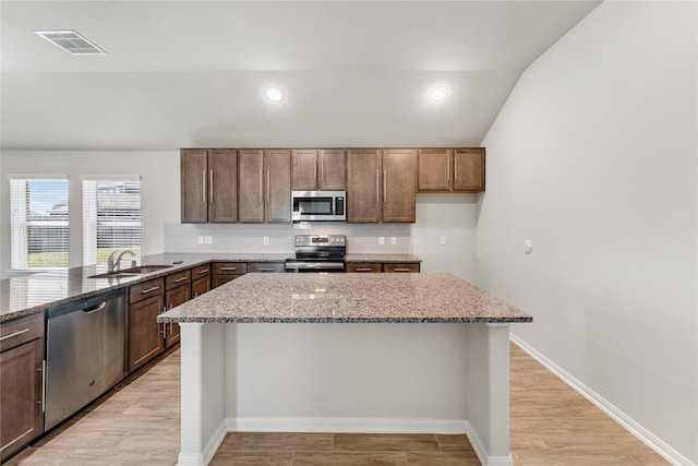 kitchen featuring visible vents, light stone countertops, stainless steel appliances, light wood-style floors, and a sink