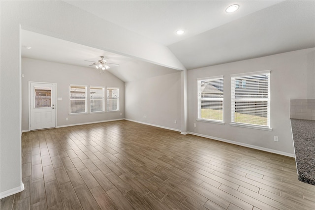 unfurnished living room featuring ceiling fan, vaulted ceiling, baseboards, and wood finished floors