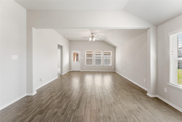 empty room with ceiling fan, baseboards, vaulted ceiling, and wood finished floors