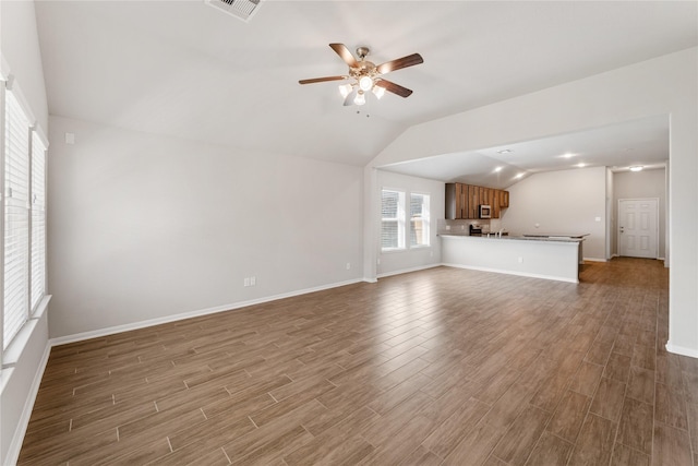 unfurnished living room with lofted ceiling, visible vents, ceiling fan, wood finished floors, and baseboards