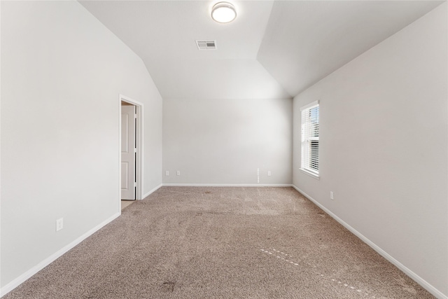 spare room with vaulted ceiling, carpet floors, visible vents, and baseboards