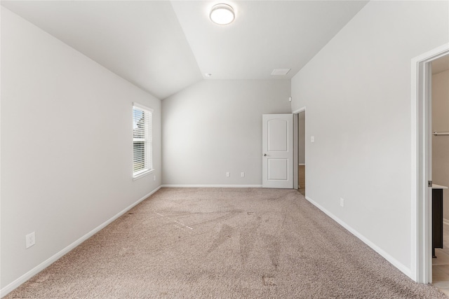 spare room with vaulted ceiling, carpet flooring, and baseboards