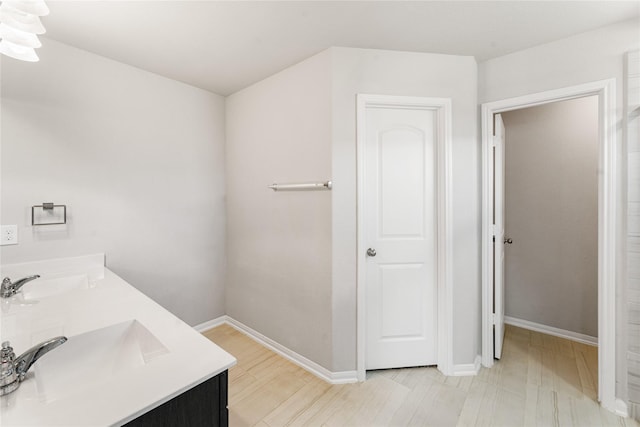 bathroom with a sink, baseboards, and double vanity