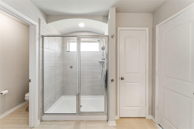 full bathroom featuring a stall shower, toilet, and baseboards