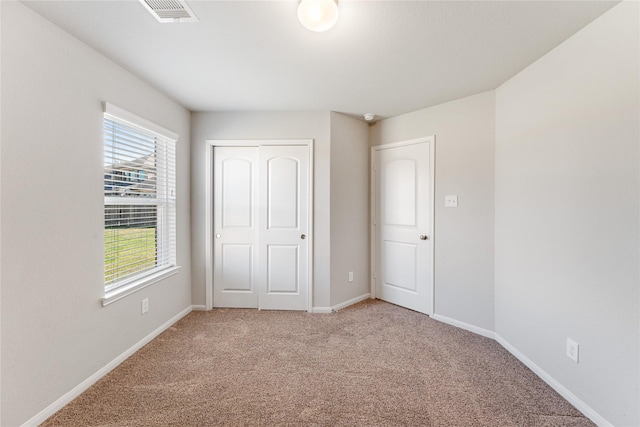 unfurnished bedroom with baseboards, a closet, visible vents, and light colored carpet