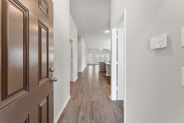 hall with baseboards and wood finished floors