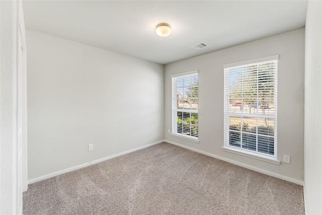 empty room with carpet, visible vents, and baseboards