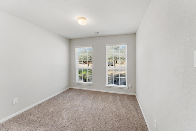 carpeted empty room with visible vents and baseboards