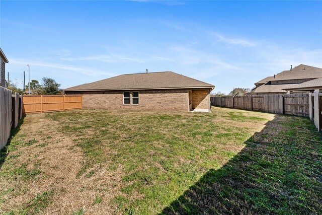 back of house featuring a yard and a fenced backyard