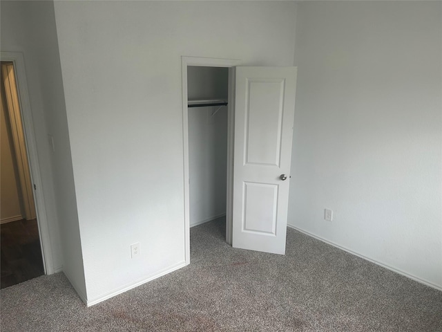 unfurnished bedroom featuring dark carpet and a closet