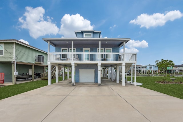 beach home featuring a carport, a front yard, central AC unit, covered porch, and a garage