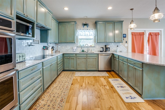 kitchen with hanging light fixtures, appliances with stainless steel finishes, and green cabinets