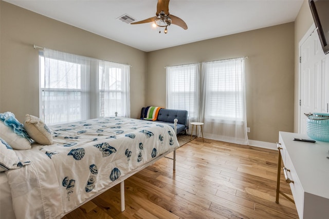 bedroom featuring ceiling fan, multiple windows, and light hardwood / wood-style flooring