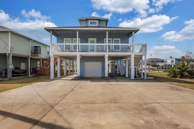 back of house featuring a carport, a garage, a porch, a balcony, and central AC unit