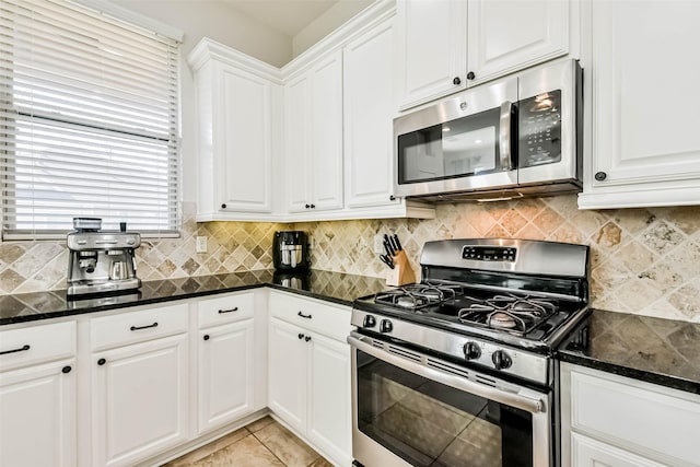 kitchen featuring white cabinetry, appliances with stainless steel finishes, decorative backsplash, and dark stone counters