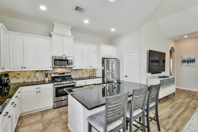 kitchen featuring a kitchen island with sink, white cabinets, and appliances with stainless steel finishes