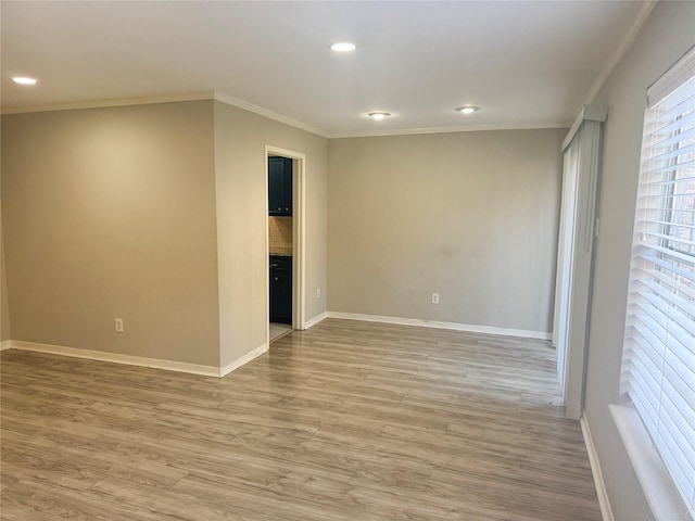 spare room with crown molding and light wood-type flooring