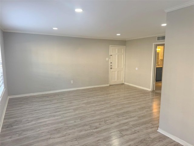 spare room featuring crown molding and light wood-type flooring