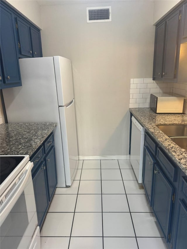 kitchen featuring white appliances, blue cabinets, decorative backsplash, and light tile patterned floors