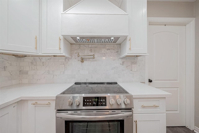 kitchen with premium range hood, white cabinets, backsplash, and stainless steel electric range