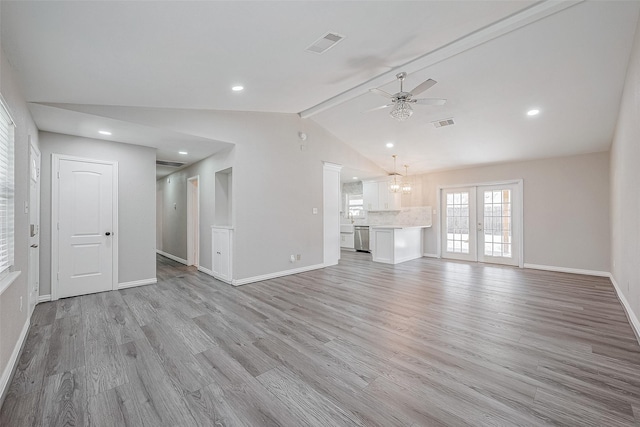 unfurnished living room with ceiling fan with notable chandelier, light wood-type flooring, french doors, and vaulted ceiling with beams