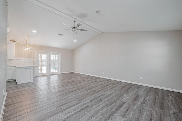 unfurnished living room featuring french doors, ceiling fan with notable chandelier, light hardwood / wood-style floors, and vaulted ceiling with beams