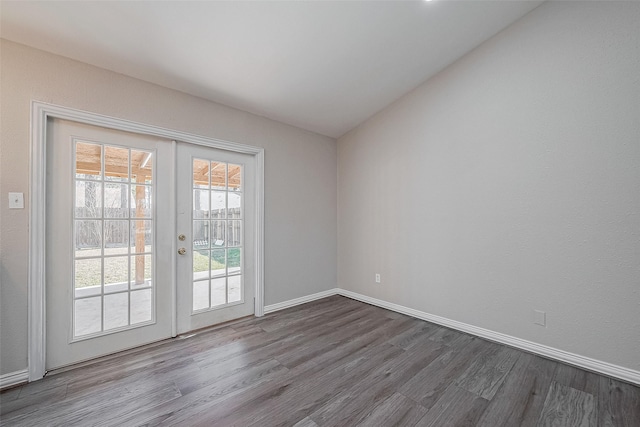 empty room with vaulted ceiling, hardwood / wood-style floors, and french doors