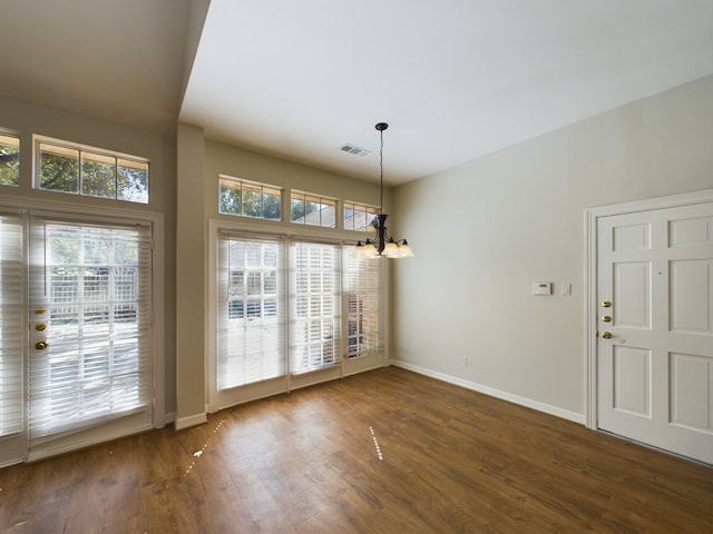 unfurnished dining area with an inviting chandelier and dark hardwood / wood-style floors