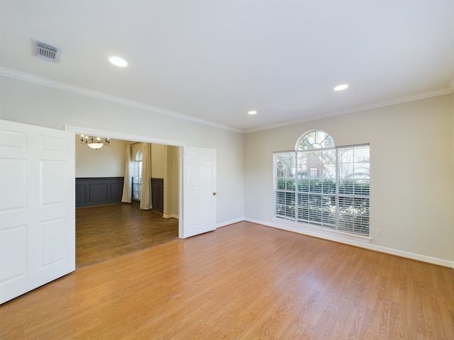 unfurnished room with hardwood / wood-style flooring, ornamental molding, and a chandelier