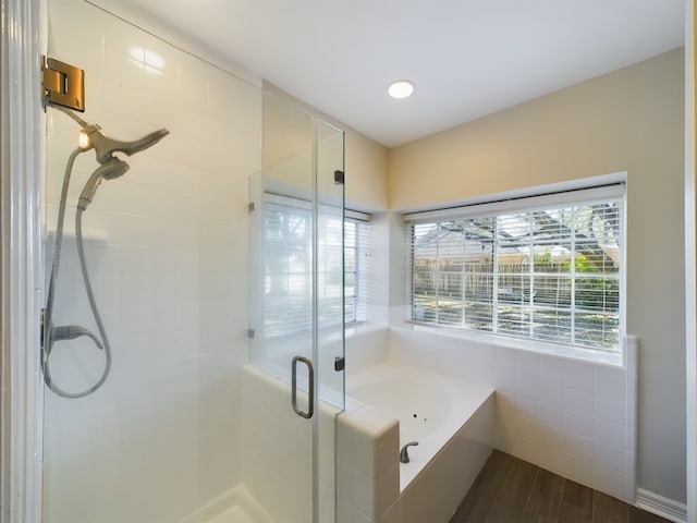 bathroom with wood-type flooring and shower with separate bathtub