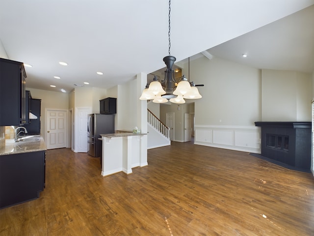 kitchen featuring light stone counters, sink, dark wood-type flooring, and stainless steel refrigerator