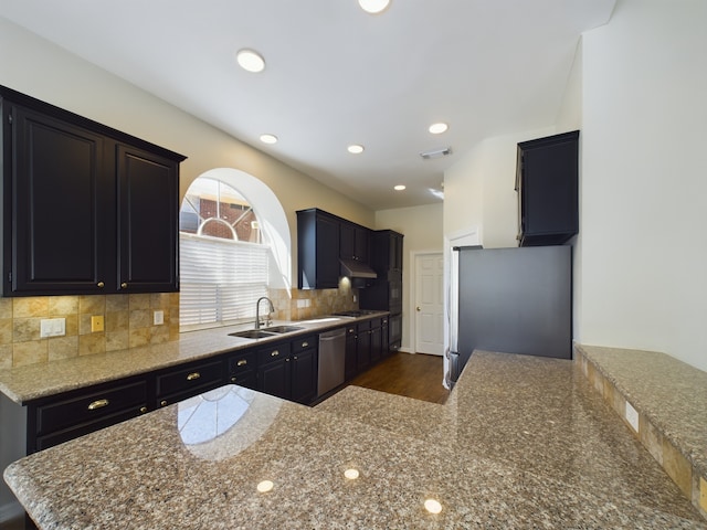 kitchen with sink, kitchen peninsula, stainless steel appliances, light stone countertops, and backsplash