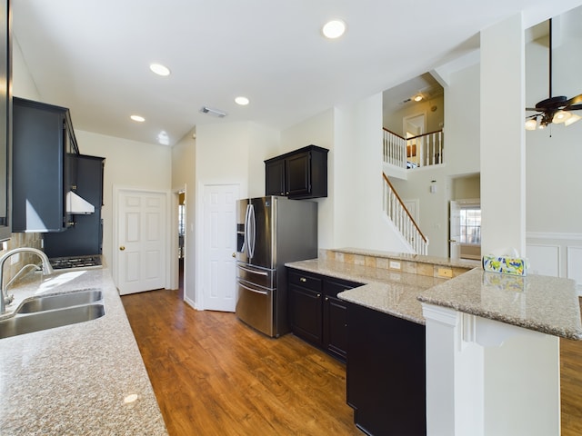 kitchen featuring sink, dark wood-type flooring, a kitchen breakfast bar, stainless steel fridge with ice dispenser, and kitchen peninsula