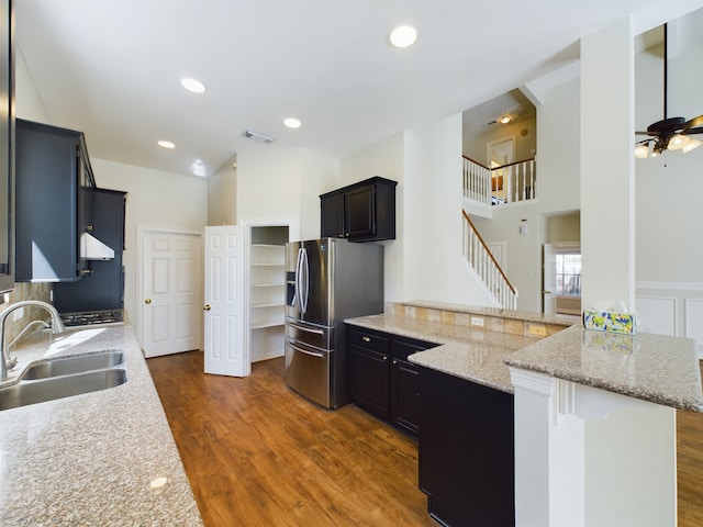 kitchen featuring sink, dark wood-type flooring, stainless steel fridge, a kitchen bar, and kitchen peninsula