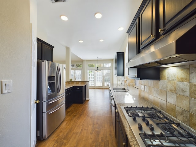 kitchen featuring extractor fan, decorative light fixtures, sink, gas stovetop, and stainless steel refrigerator with ice dispenser