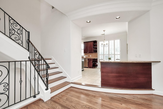 interior space featuring pendant lighting, crown molding, light hardwood / wood-style flooring, a notable chandelier, and stainless steel dishwasher