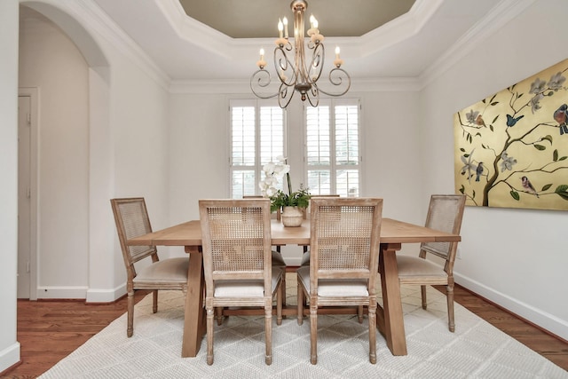 dining room with crown molding, hardwood / wood-style floors, a tray ceiling, and a chandelier