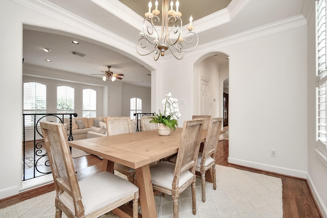 dining space with crown molding, a tray ceiling, ceiling fan with notable chandelier, and hardwood / wood-style floors