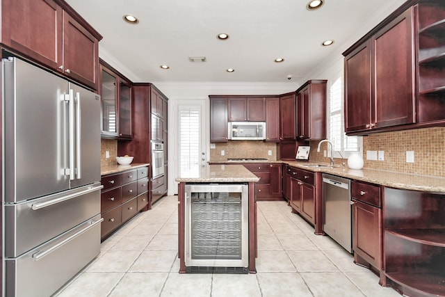 kitchen featuring sink, appliances with stainless steel finishes, wine cooler, light stone counters, and a kitchen island