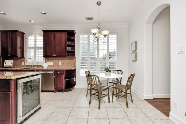 kitchen with backsplash, light stone counters, ornamental molding, stainless steel dishwasher, and beverage cooler