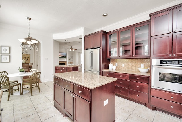 kitchen with a kitchen island, appliances with stainless steel finishes, decorative light fixtures, tasteful backsplash, and light stone counters