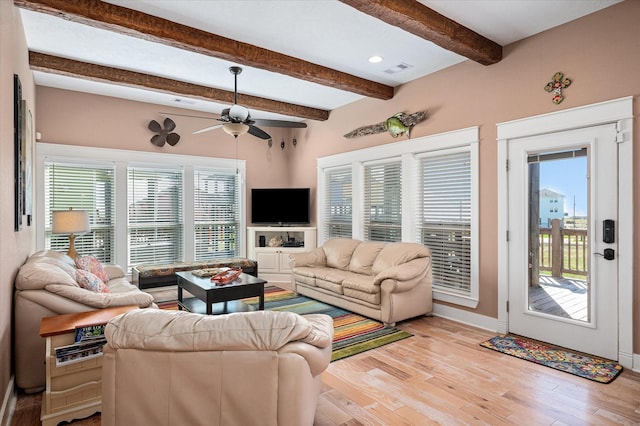 living room with ceiling fan, light hardwood / wood-style flooring, beamed ceiling, and a healthy amount of sunlight