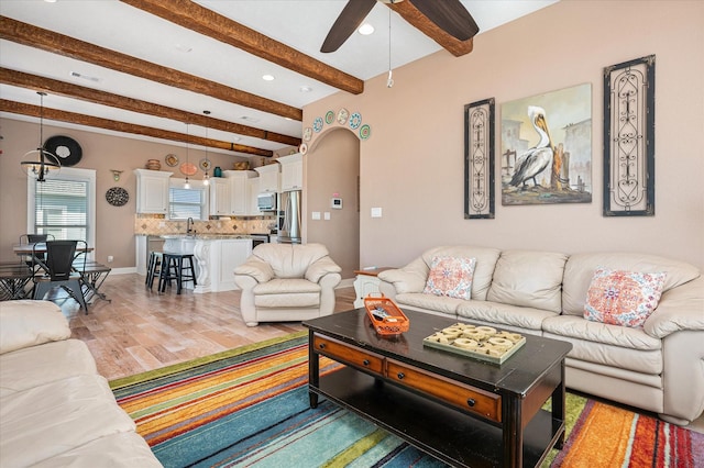 living room with sink, beam ceiling, ceiling fan, and light wood-type flooring