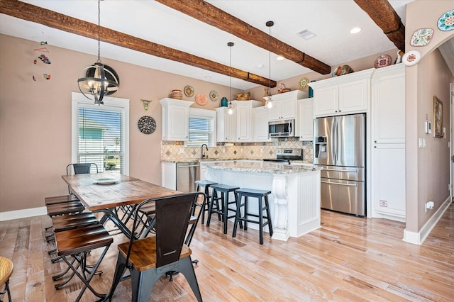 dining room featuring beamed ceiling, an inviting chandelier, and light wood-type flooring