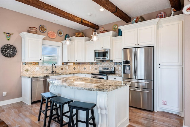 kitchen with pendant lighting, white cabinetry, appliances with stainless steel finishes, and a kitchen island