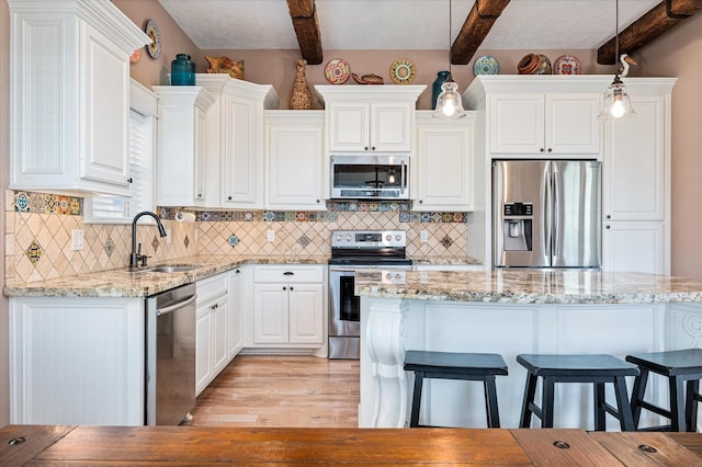 kitchen with pendant lighting, sink, white cabinets, and appliances with stainless steel finishes