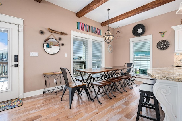 dining area with beamed ceiling, a chandelier, and light hardwood / wood-style flooring