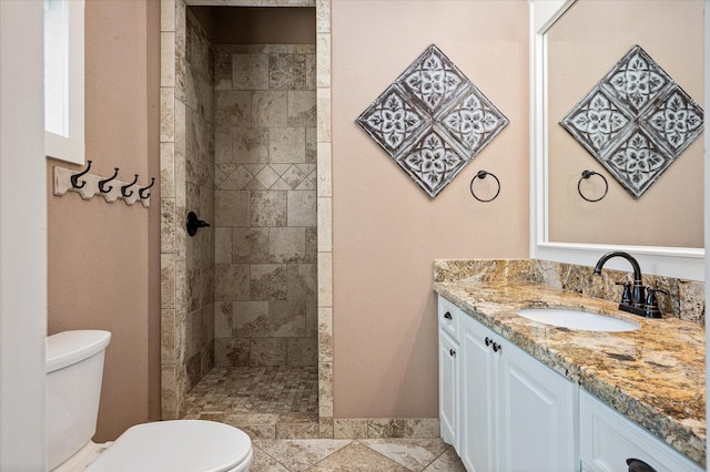 bathroom featuring tiled shower, vanity, and toilet