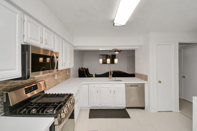 kitchen featuring sink, white cabinetry, hanging light fixtures, stainless steel appliances, and decorative backsplash