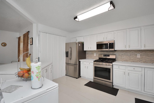 kitchen featuring backsplash, a textured ceiling, stainless steel appliances, and white cabinets